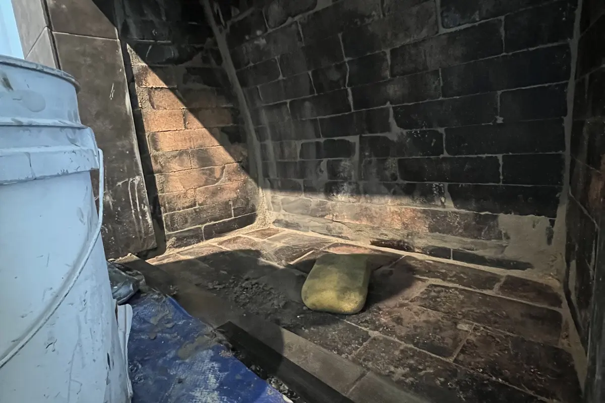 Firebox with soot and creosote buildup before chimney sweep