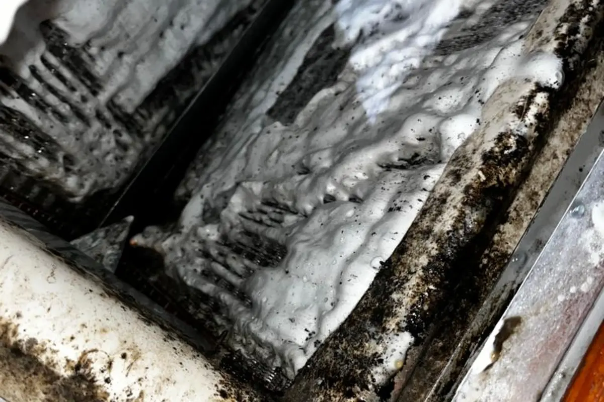 Dirty evaporator coil caked with grime and debris before foam cleaning treatment